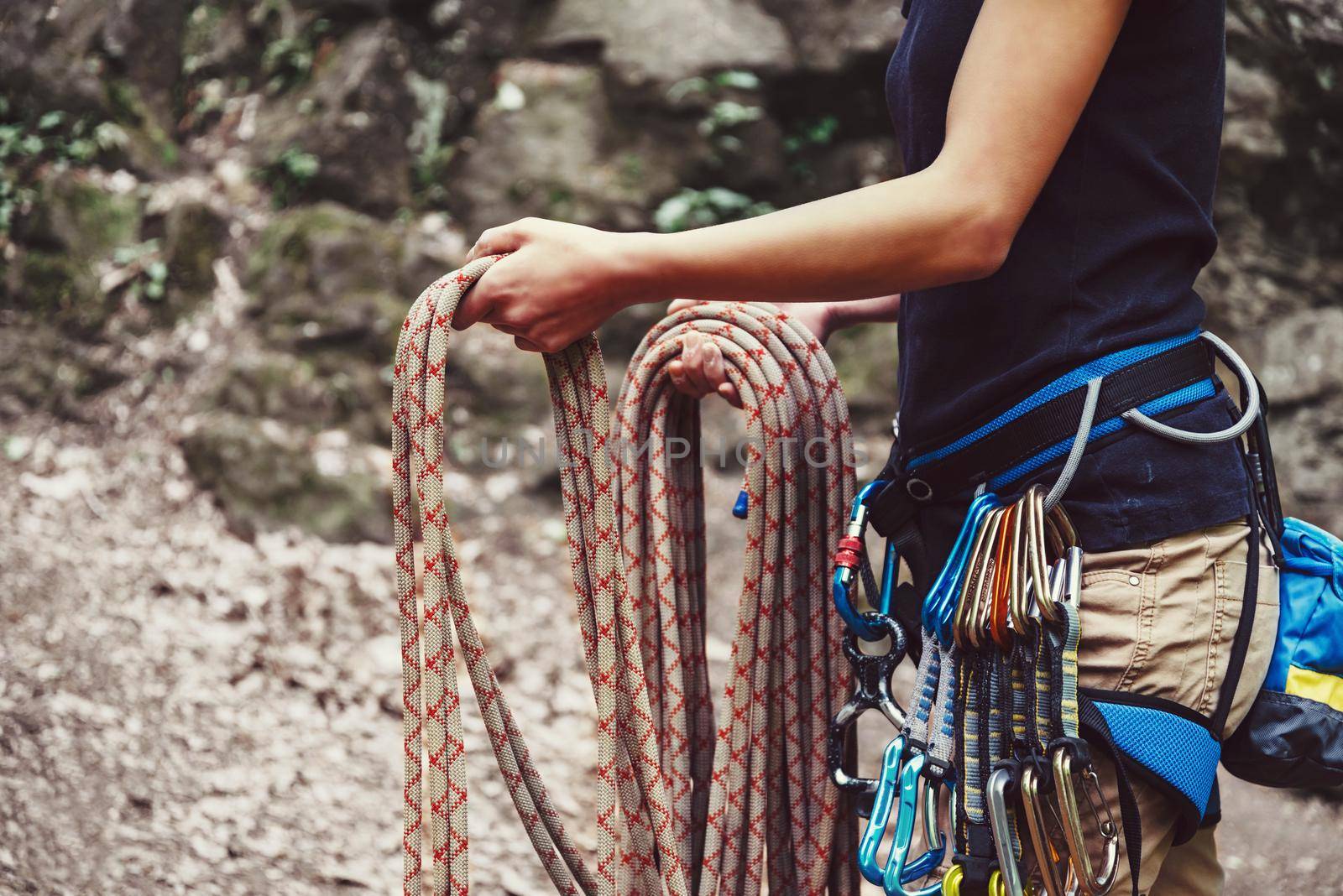 Woman holding climbing rope near the rock by alexAleksei