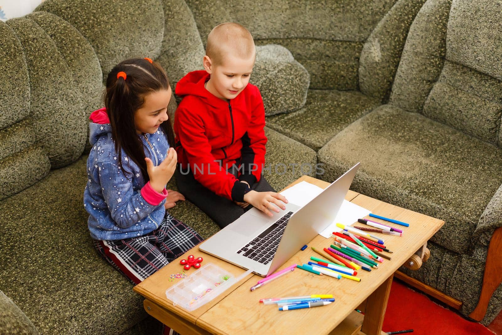 Distance learning online education. school boy and girl studying at home with laptop notebook and doing homework. Sitting at a table by Andelov13