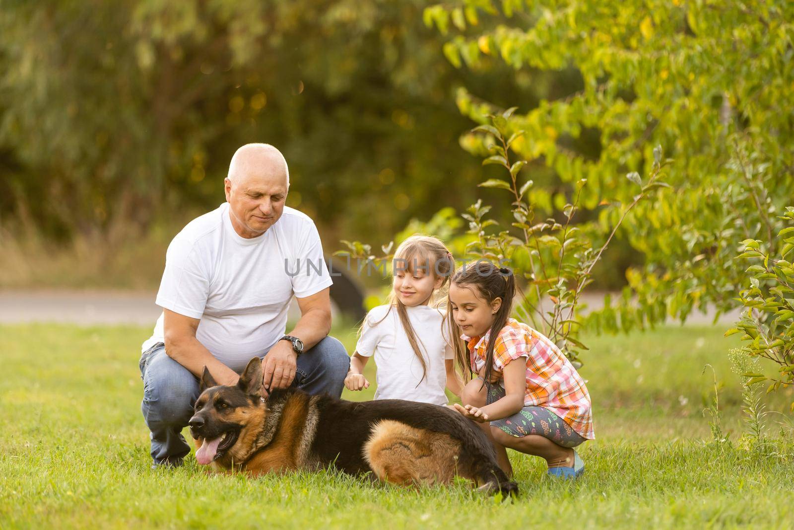 grandfather and two granddaughters are walking in the park