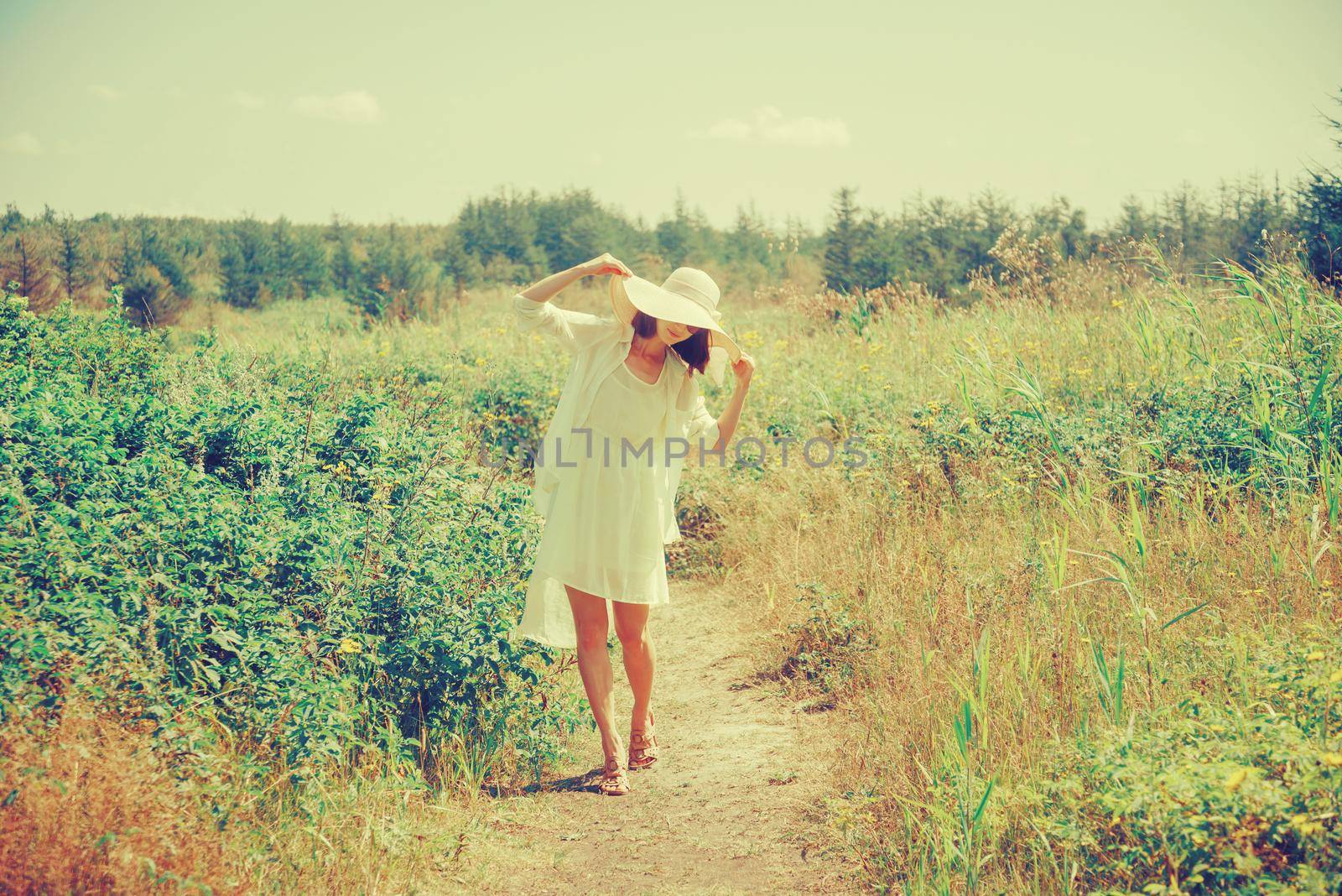 Smiling young woman walking on path in summer park, concept of summer mood. Image with instagram color effect