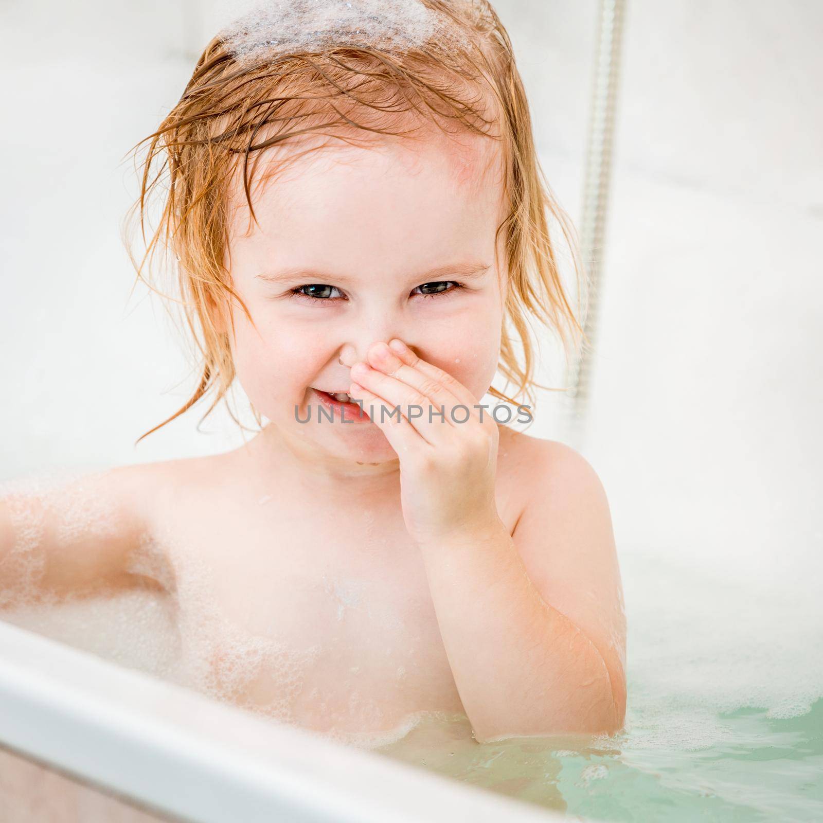 cute two year old baby bathes in a bath with foam closeup