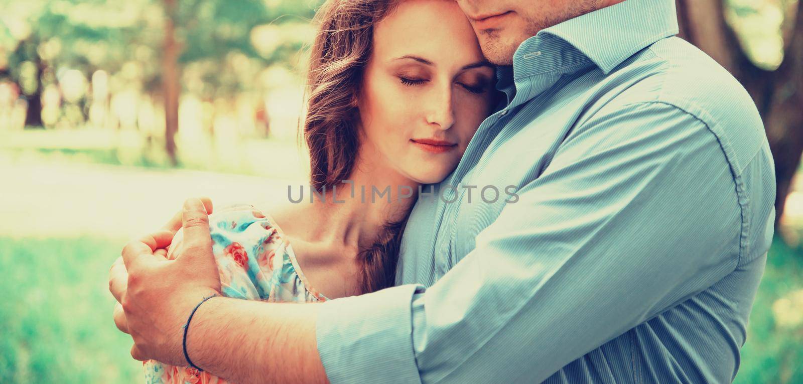 Young couple in love resting in summer park. Man embracing woman with closed eyes, tender scene. Image with instagram color effect