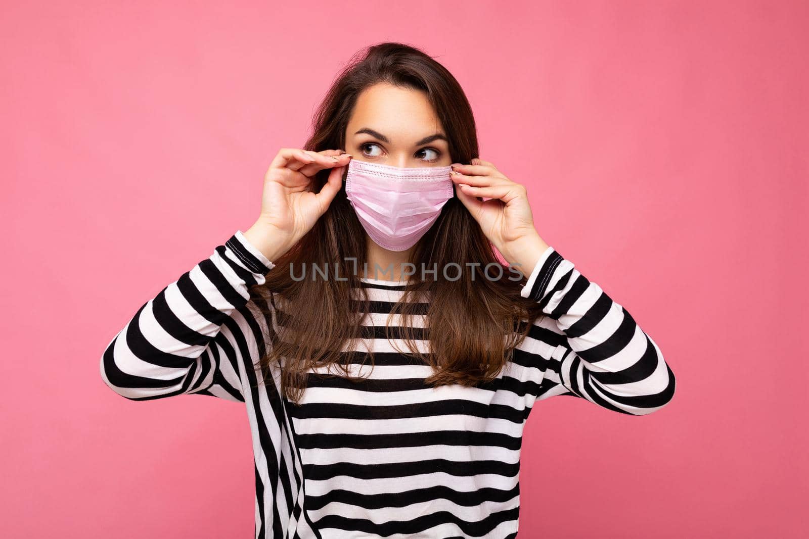 Shot of young attractive woman wearing mediacal face mask isolated over background wall. Protection against COVID-19 by TRMK
