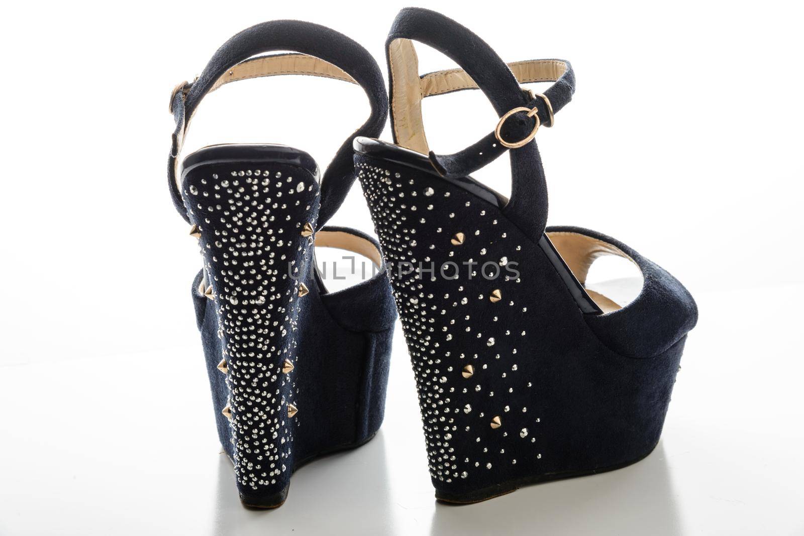 Stylish women&#39;s blue sandals with high heels with studs on a white background.