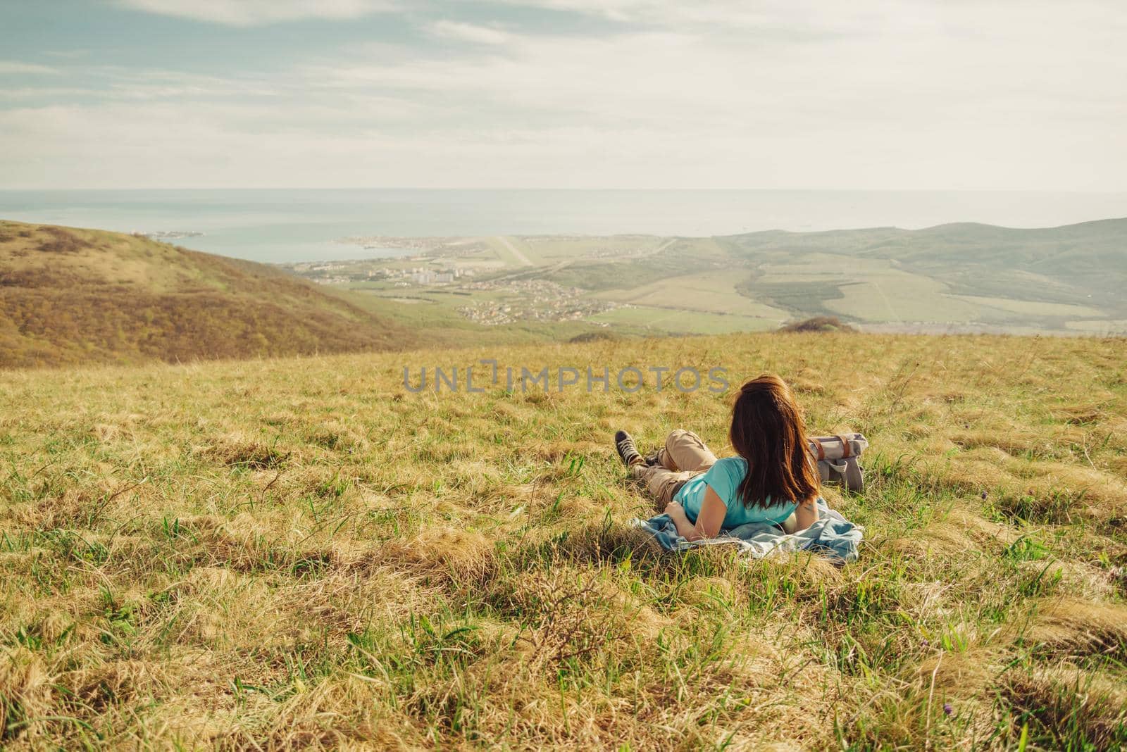 Hiker young woman lying on summer meadow in the mountains