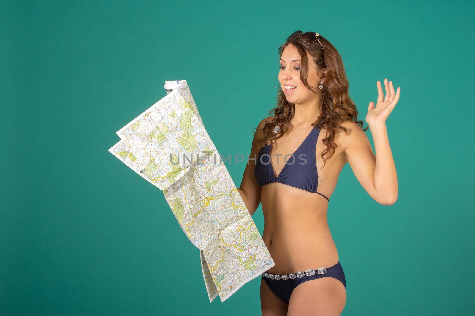Travel concept. Studio portrait of pretty young woman taking image with map on green background