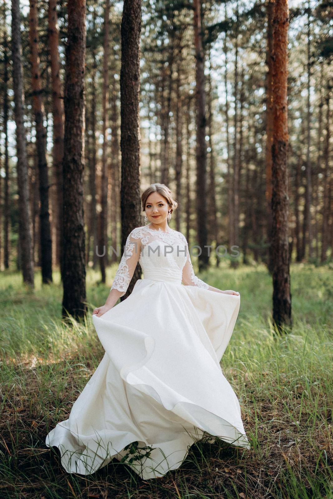 the bride walking in a pine forest on a bright day