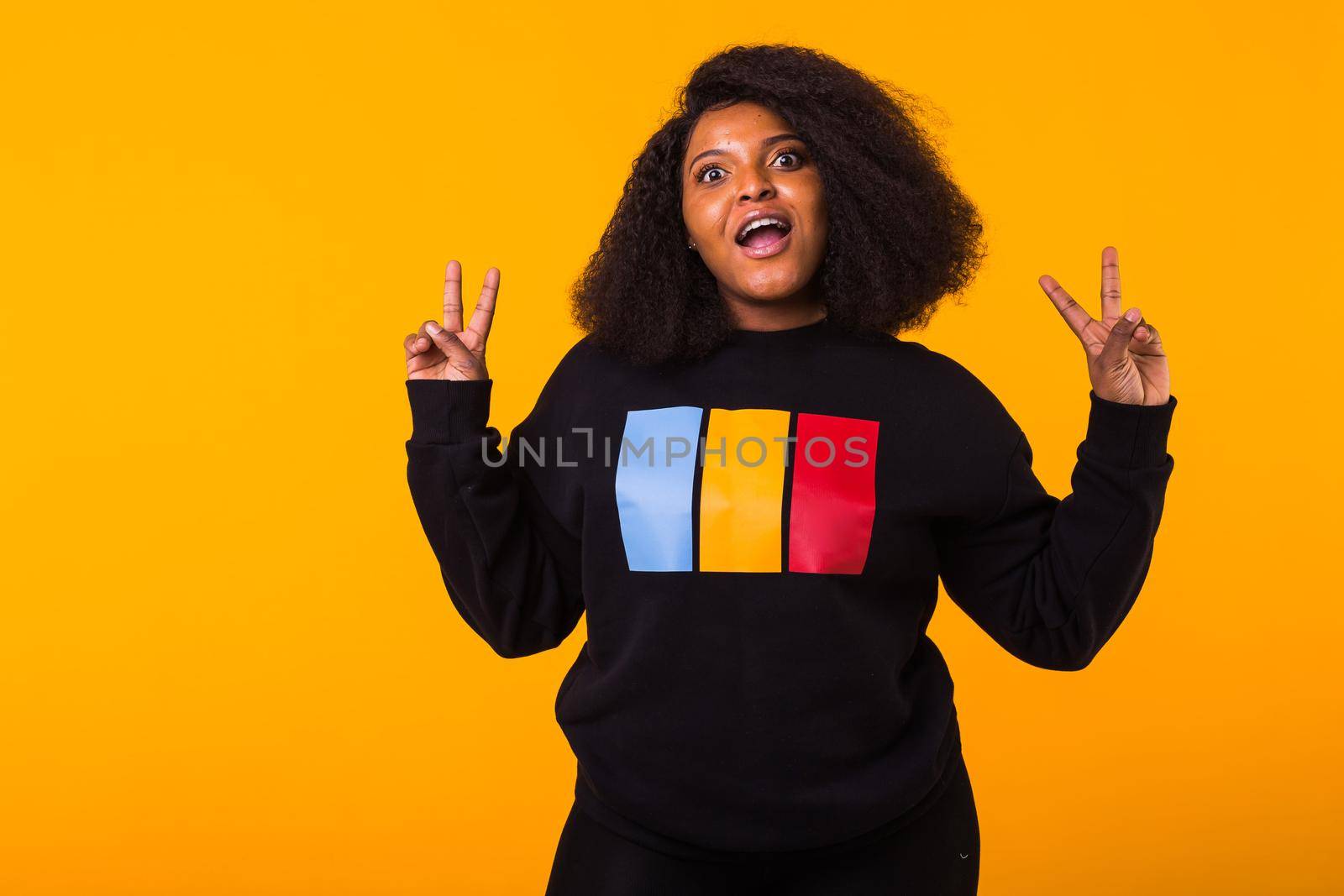 Youth fashion concept - Confident sexy black woman in stylish hoodie having fun on yellow background