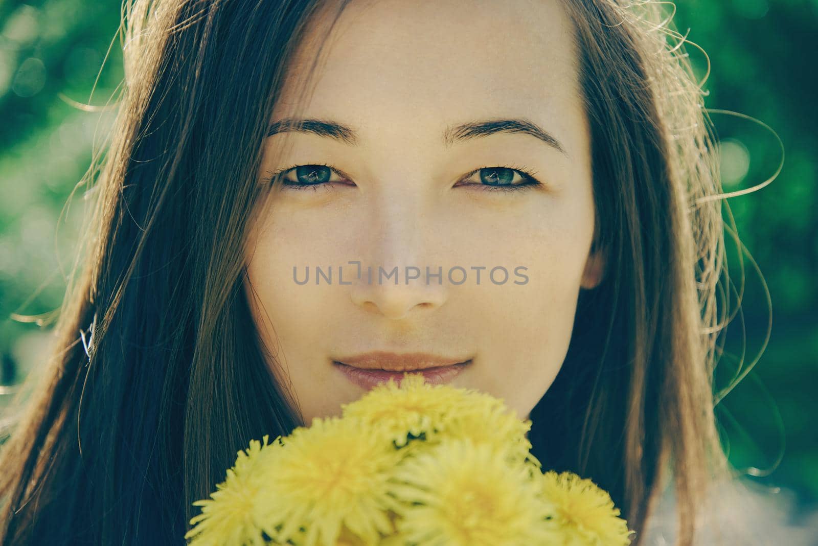 Portrait of beautiful young woman with bouquet of yellow dandelions outdoor in summer, concept of summer mood