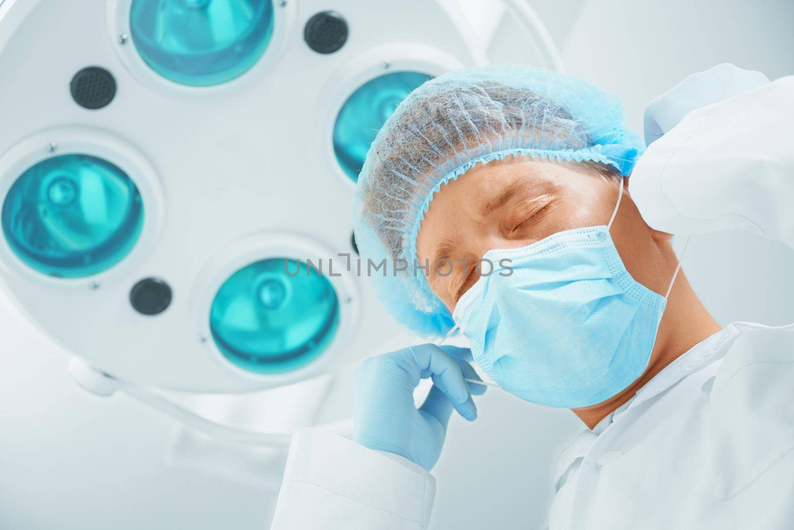 Surgeon takes off his protective mask after operation by alexAleksei