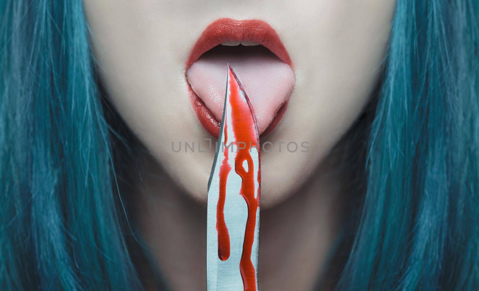 Dangerous young woman licking a knife in blood. Halloween or horror theme