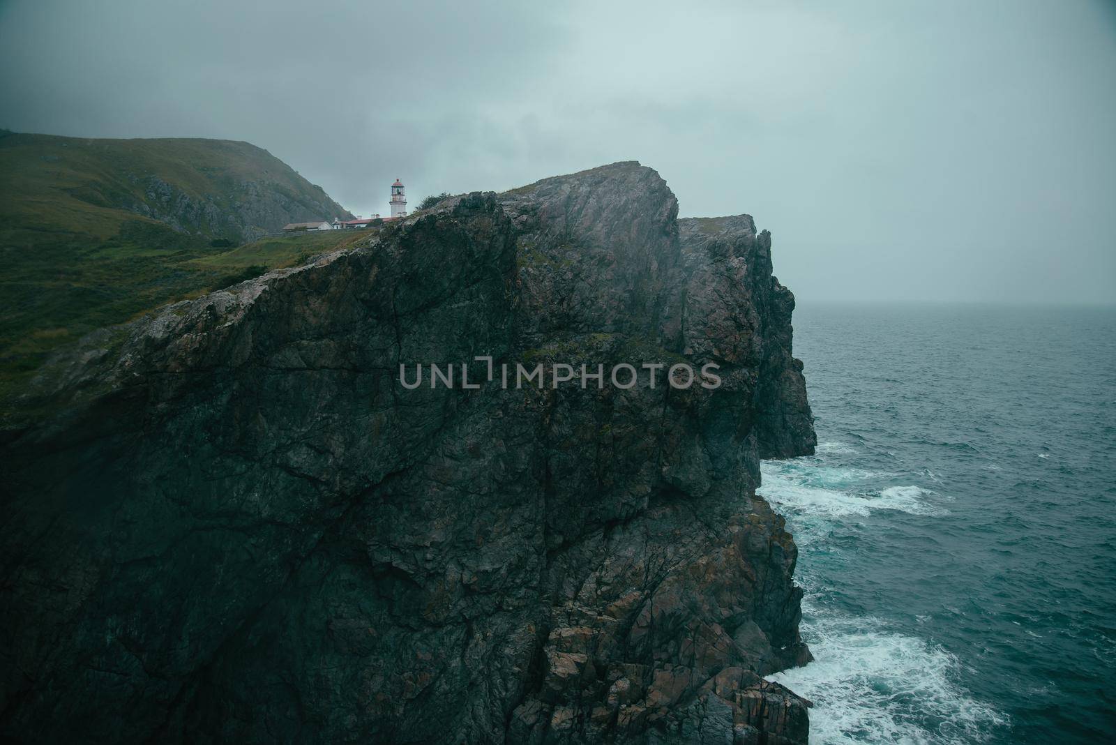 Landscape of rocky high coast near the sea. Lighthouse on coast