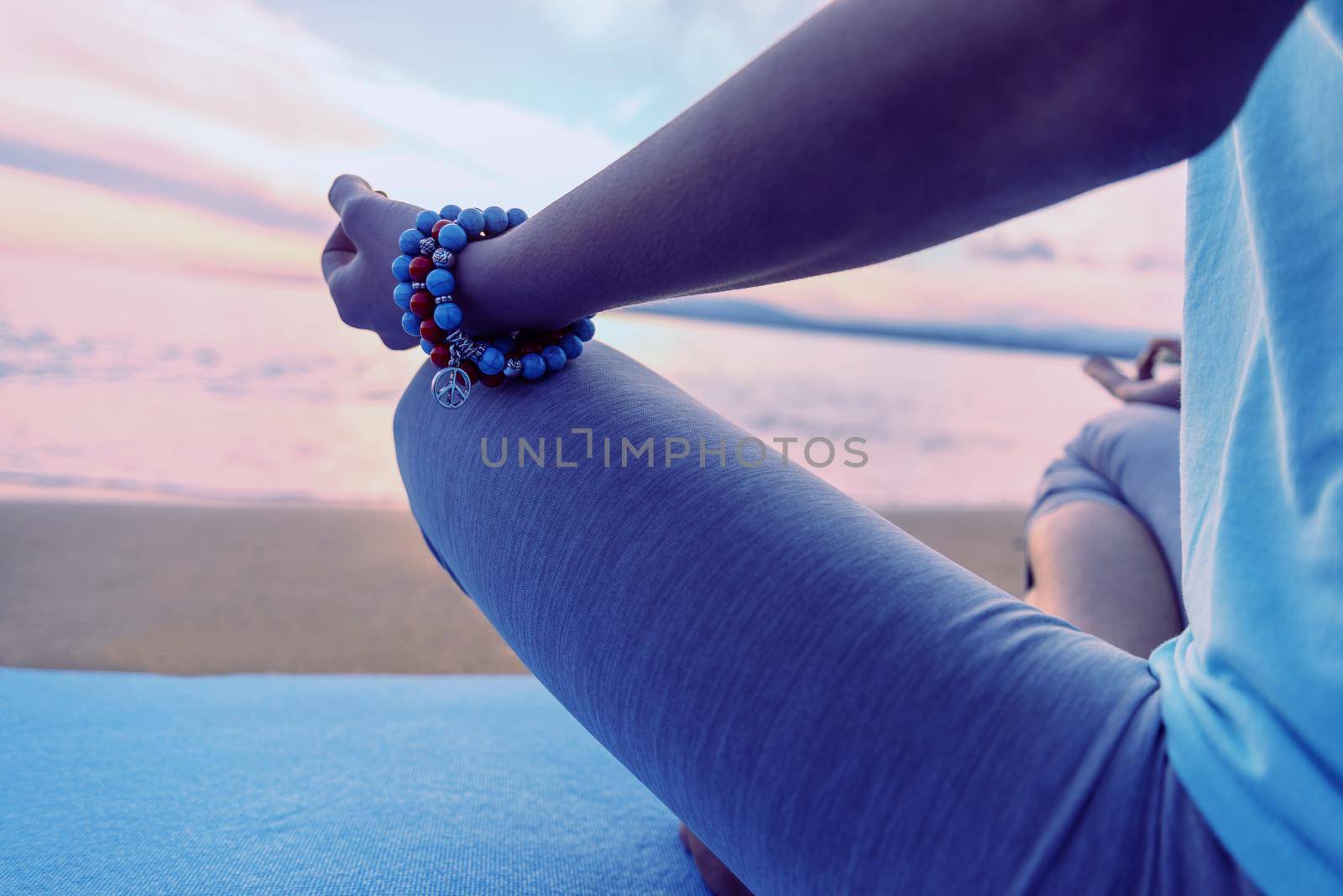 Woman meditating in pose of lotus on beach in summer in the morning, close-up