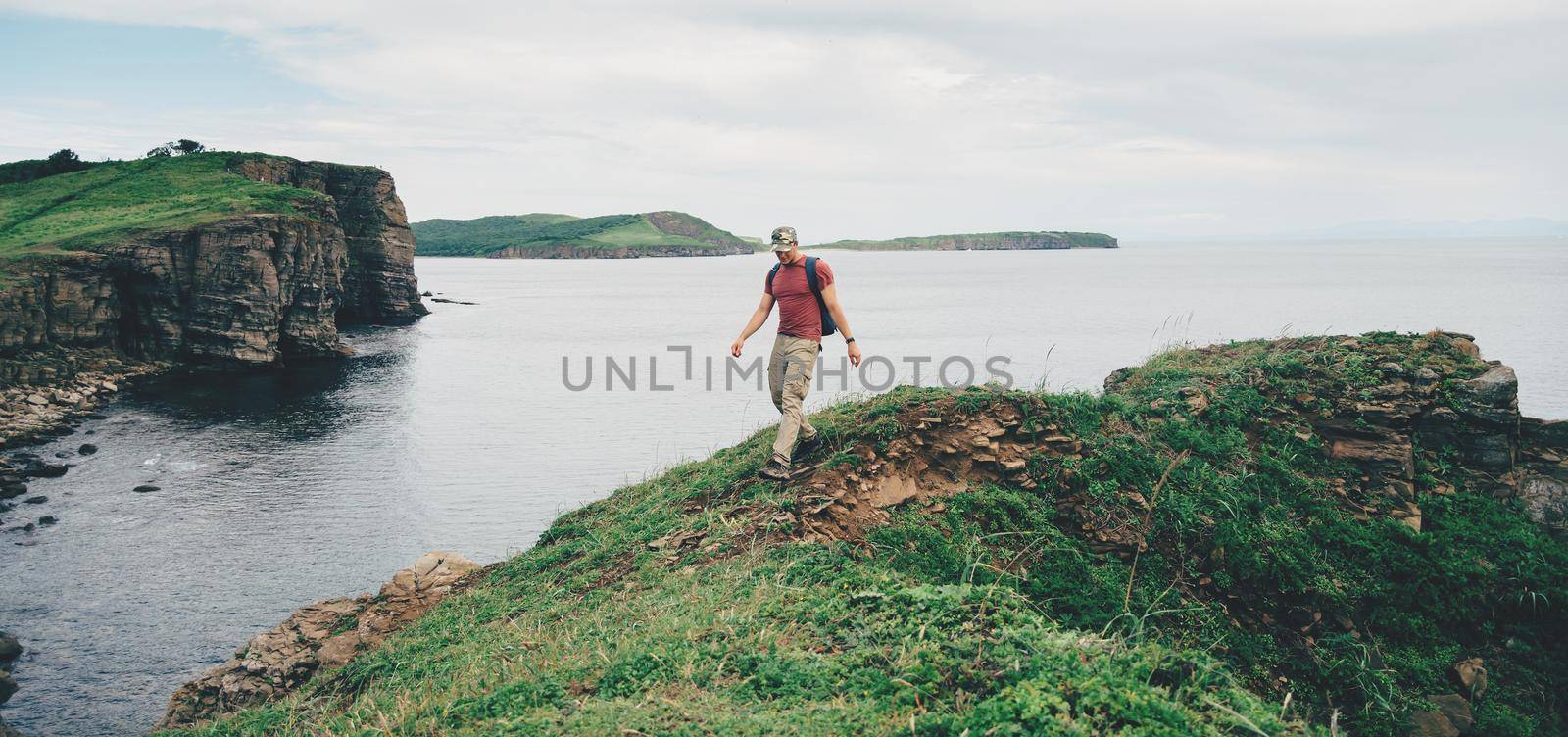 Hiker young man walking on coastline near the sea in summer