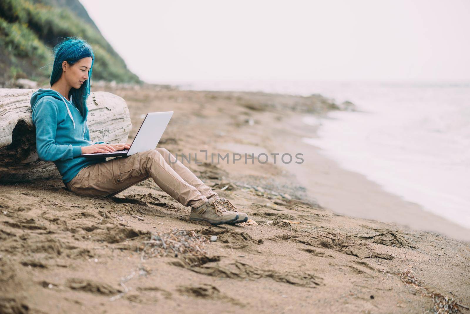 Freelancer girl working on laptop on beach by alexAleksei