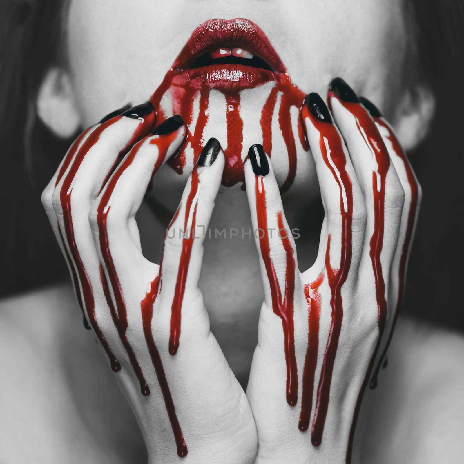 Young woman touching her face in blood. Halloween and horror theme. Black and white image with red elements