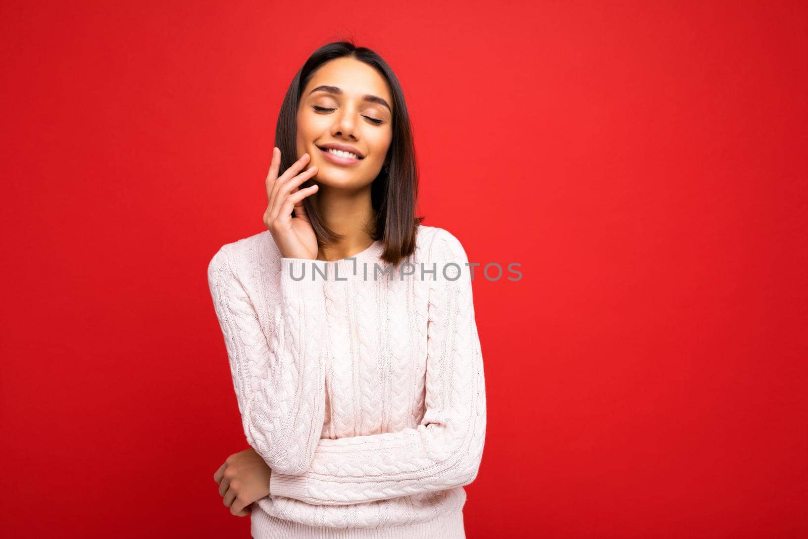 Portrait of positive cheerful cute smiling young brunette woman in casual sweater isolated on red background with copy space.