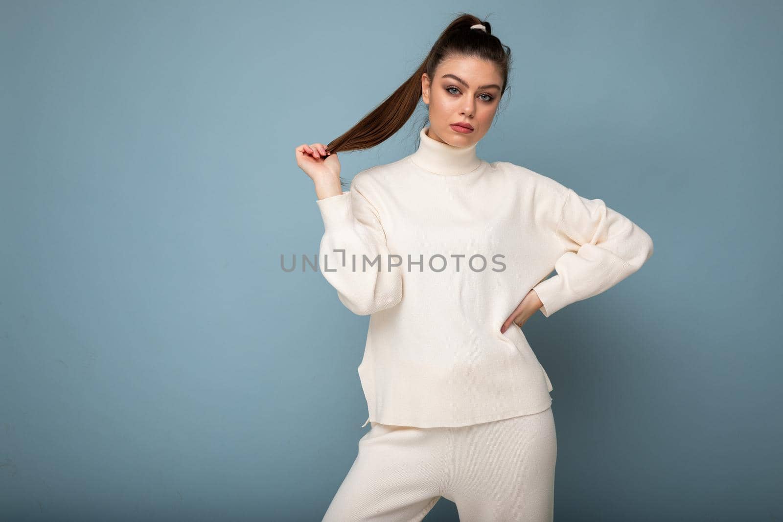 Young beautiful european fashion woman wearing white sweater isolated over blue background with serious expression on face. Empty space