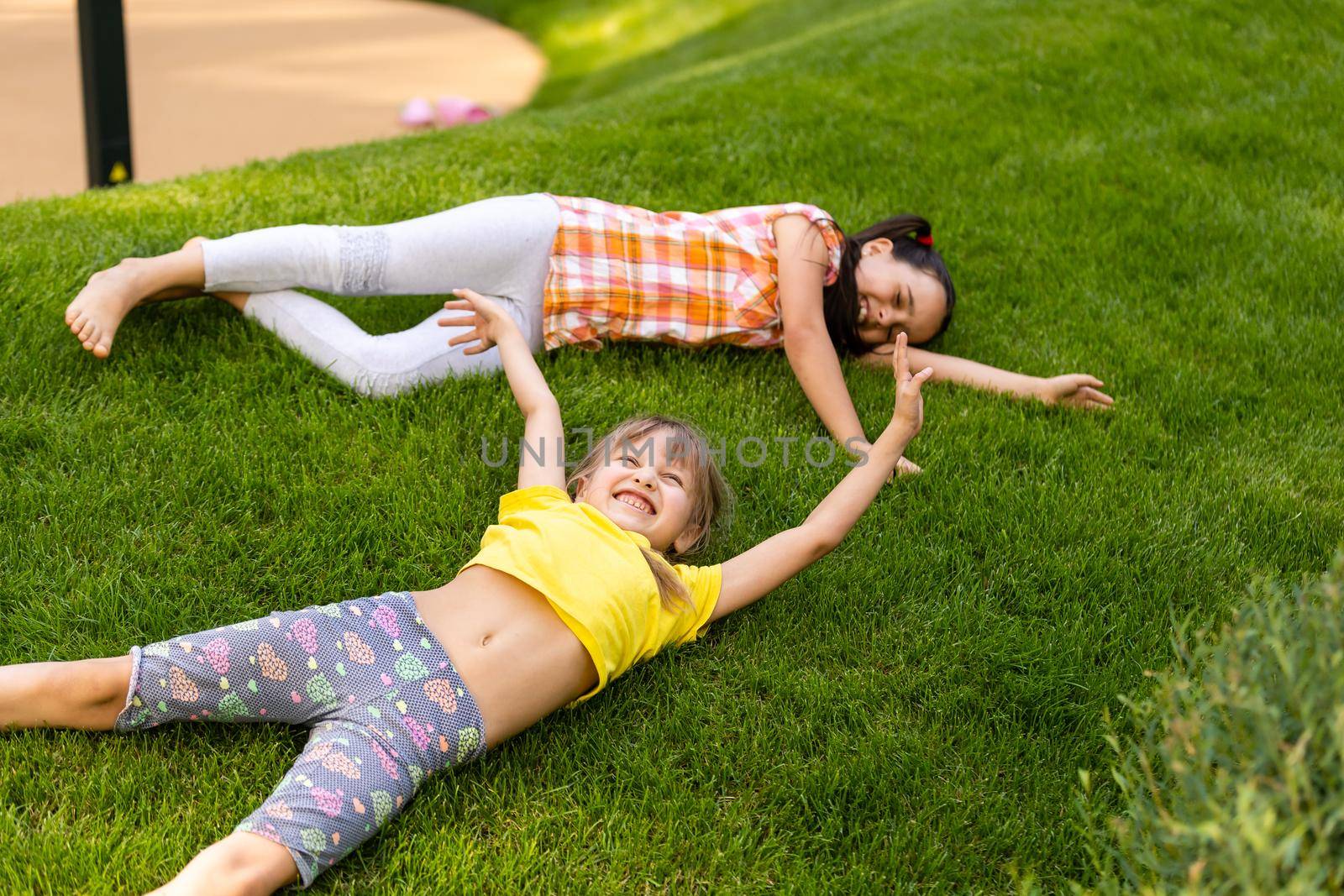 Portrait of two little girls sisters fighting on home backyard. Friends girls having fun. Lifestyle candid family moment of siblings quarreling playing together.