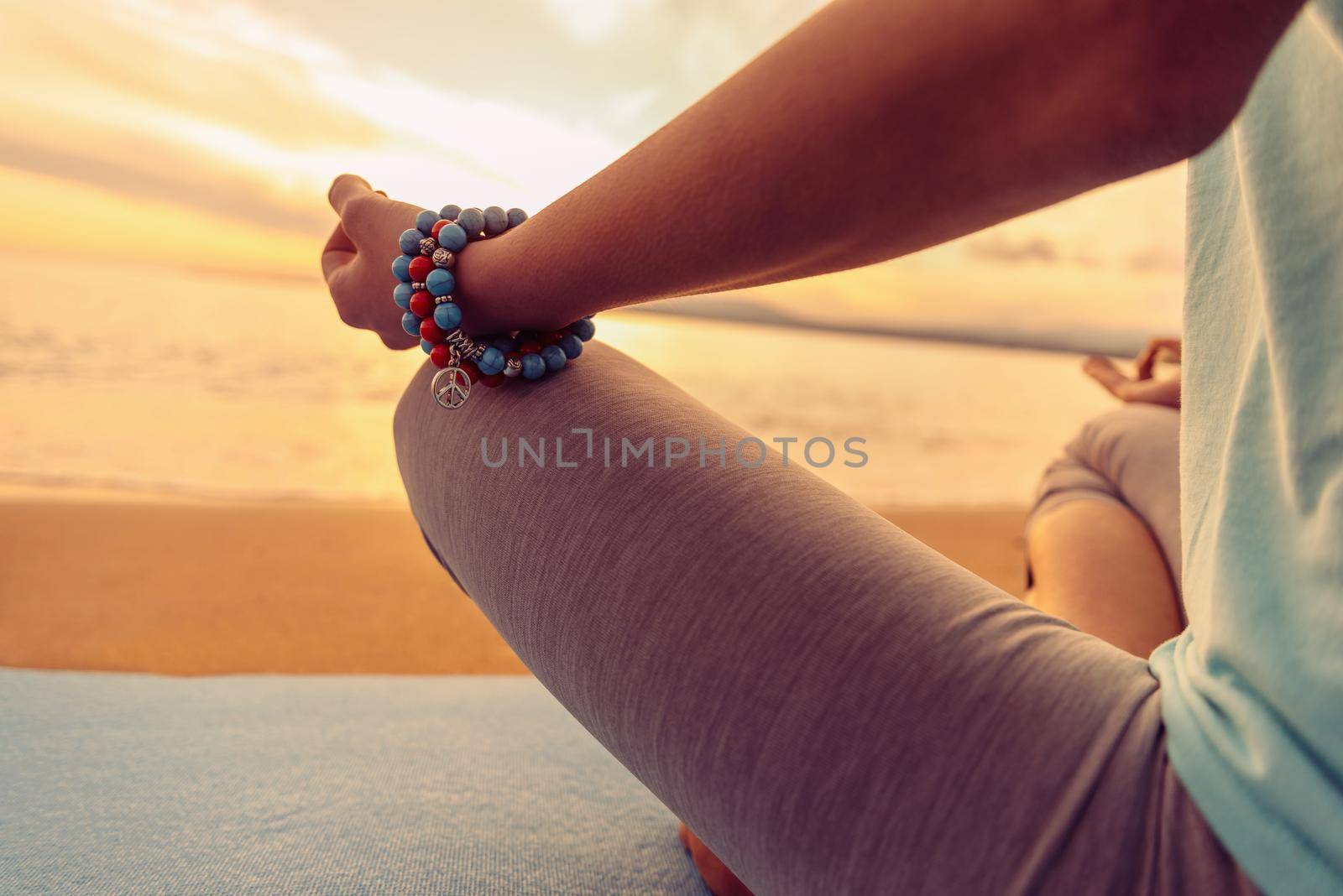 Woman meditating in pose of lotus on beach in summer, close-up