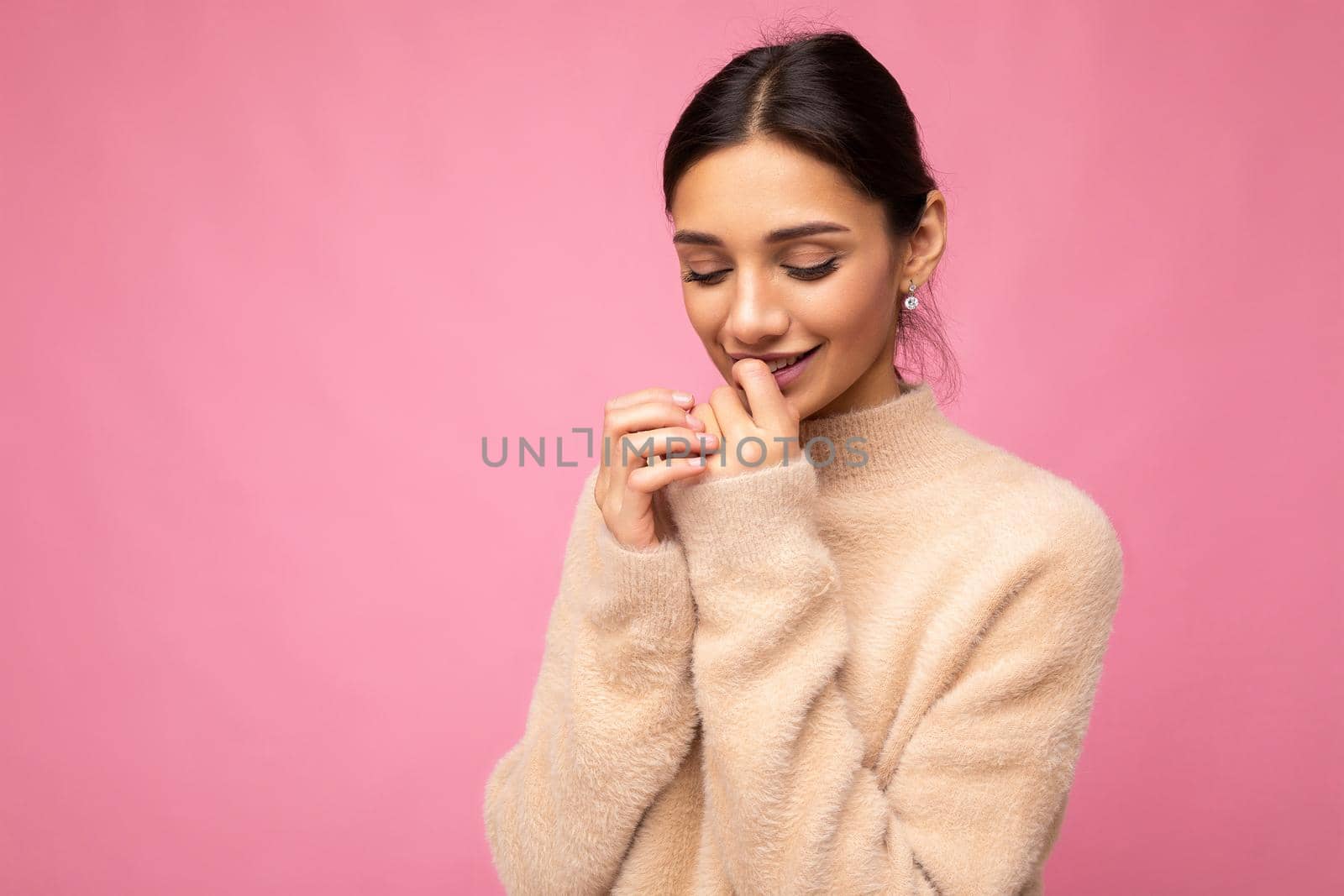 Portrait of young positive smiling tender winsome happy beautiful brunette woman with sincere emotions wearing casual beige jersey isolated over pink background with free space.