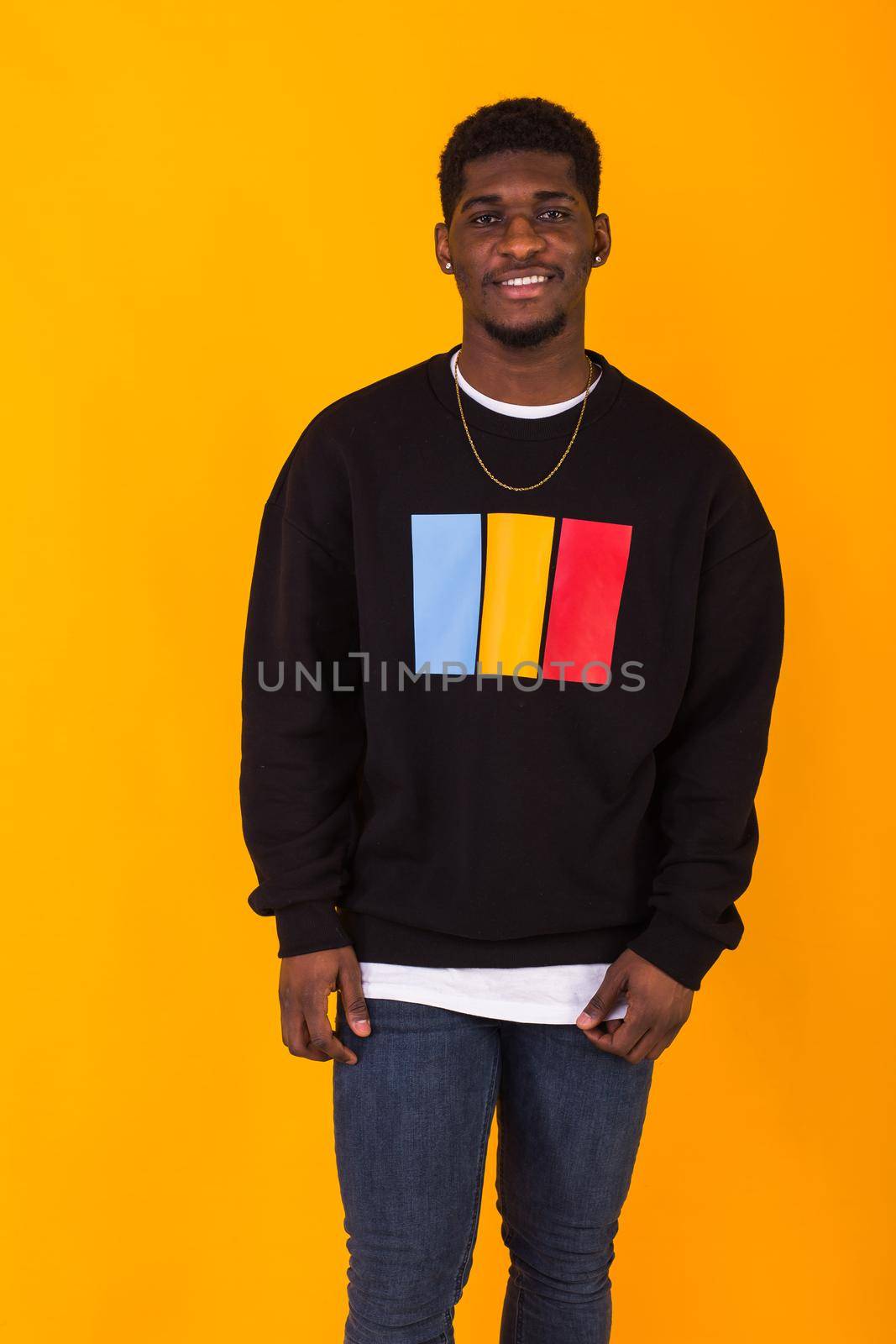 Street fashion concept - Studio shot of young handsome African man wearing sweatshirt against yellow background. by Satura86