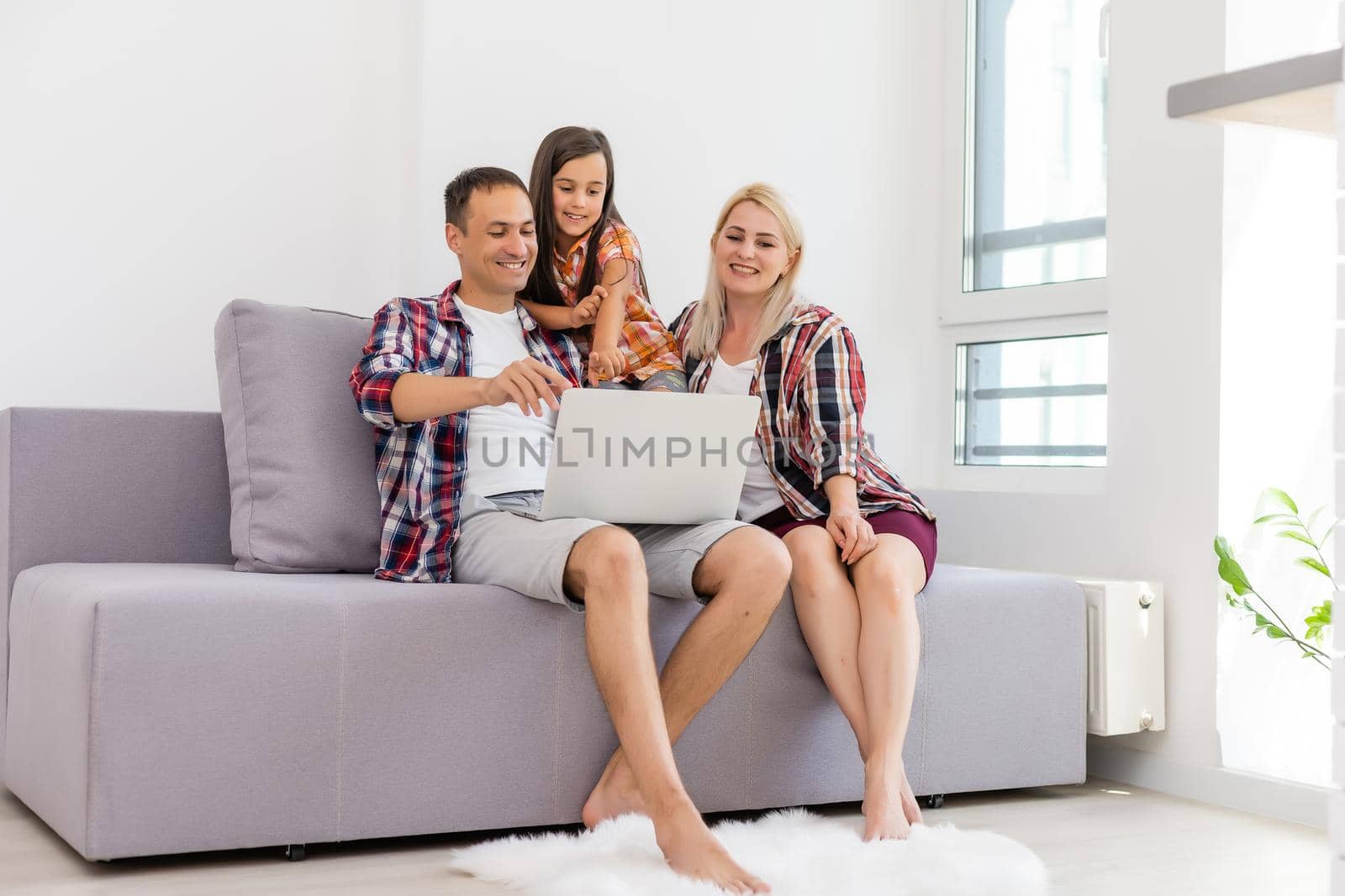 Happy family using laptop together on sofa in house by Andelov13