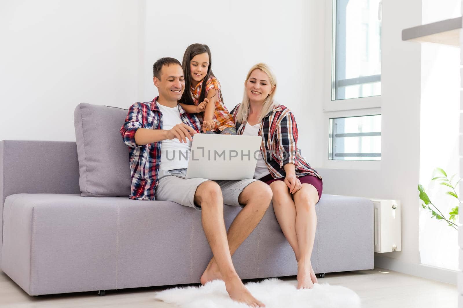 Happy family using laptop together on sofa in house