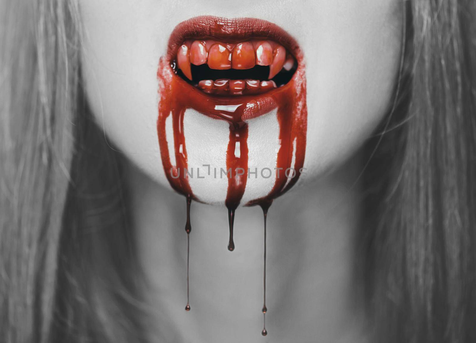 Spooky vampire woman, close-up of mouth with teeth in red blood. Halloween or horror theme. Black and white image with red elements