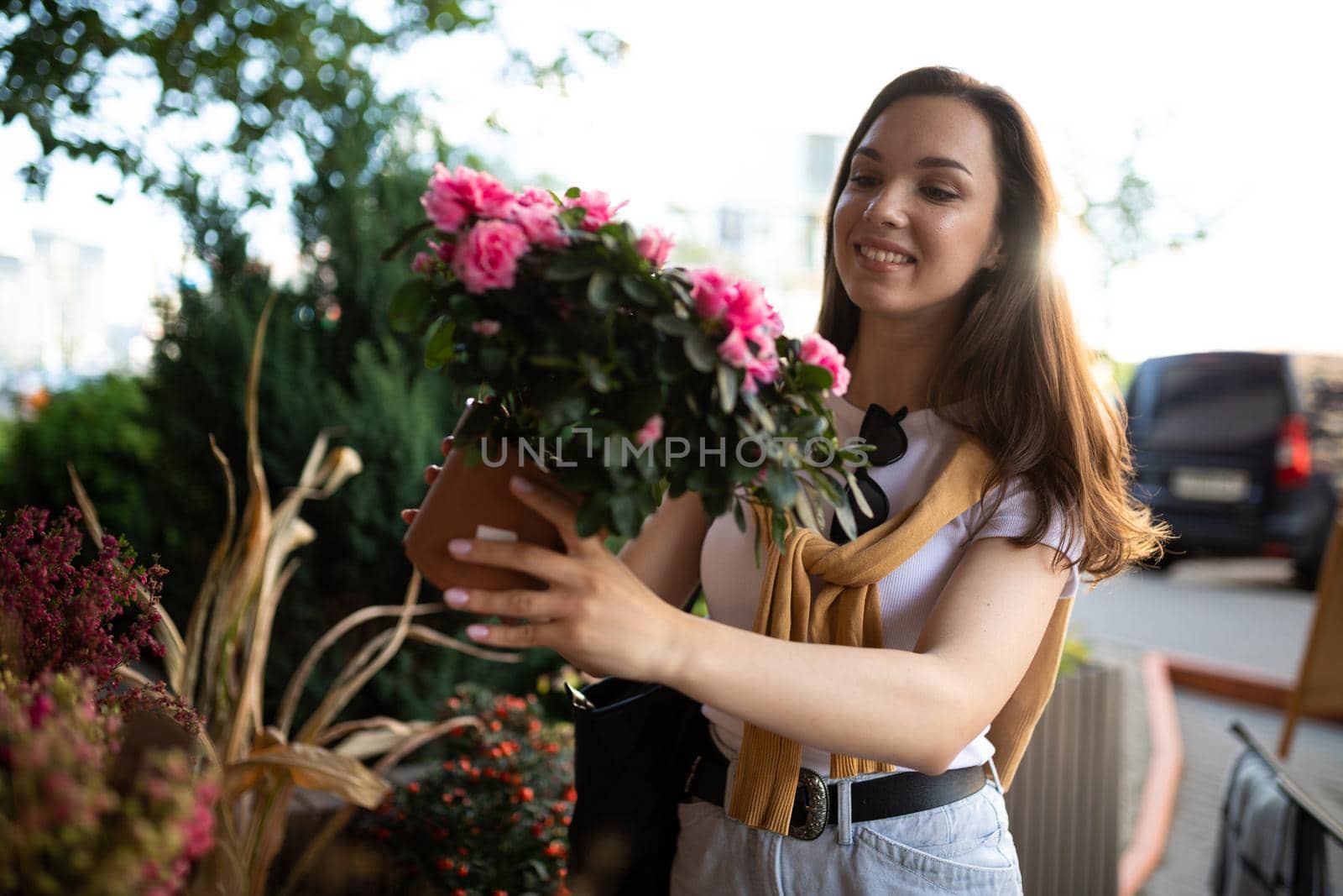 young beautiful brunette woman enjoying flowers in pots on the porch of a flower shop.