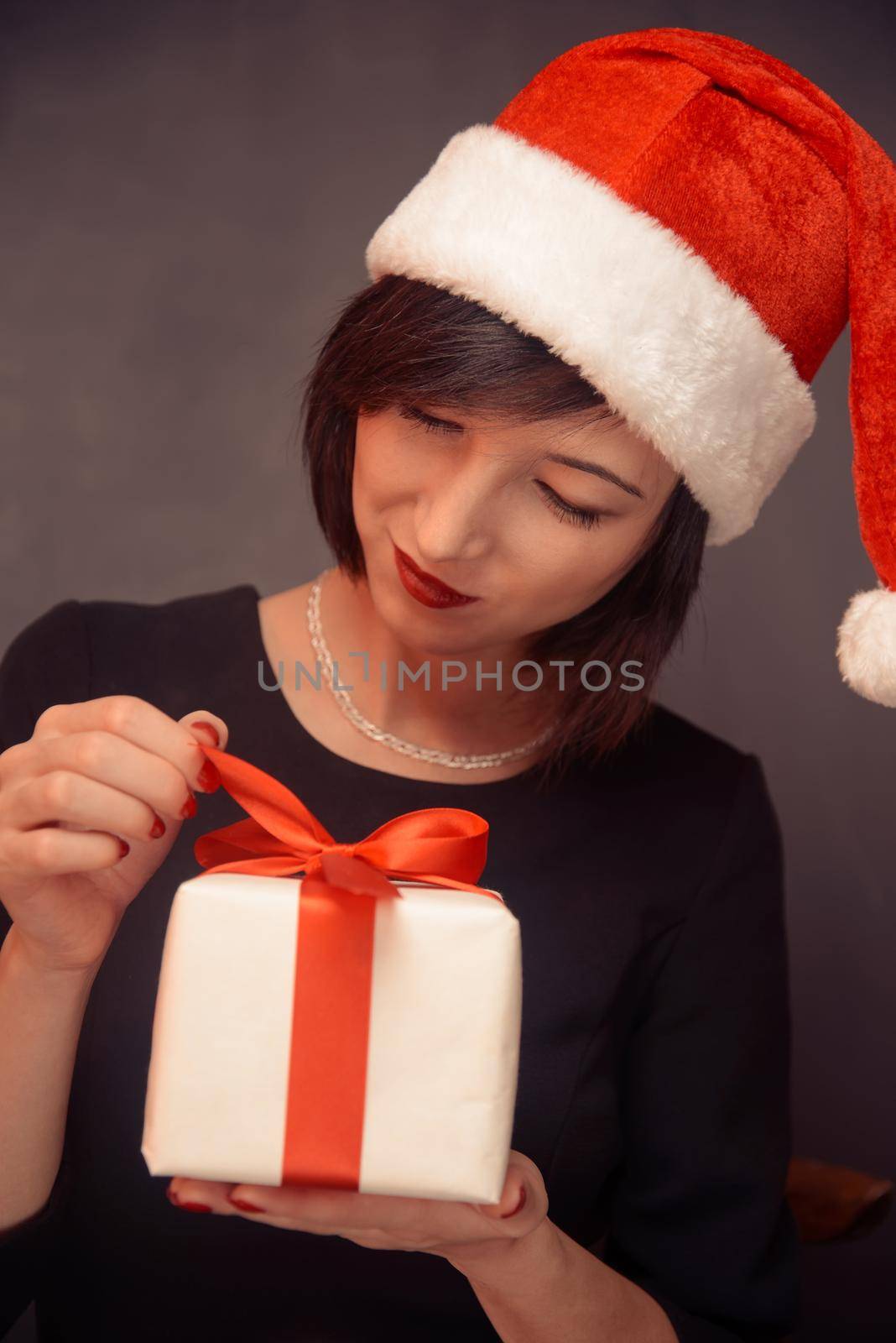 Beautiful woman is opening gift box with red bow