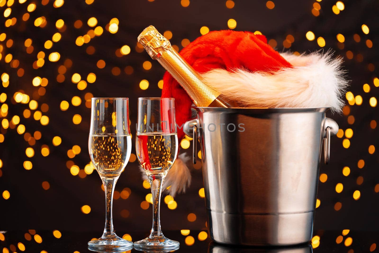 Champagne and Santa Claus hat on blurred garland background front view