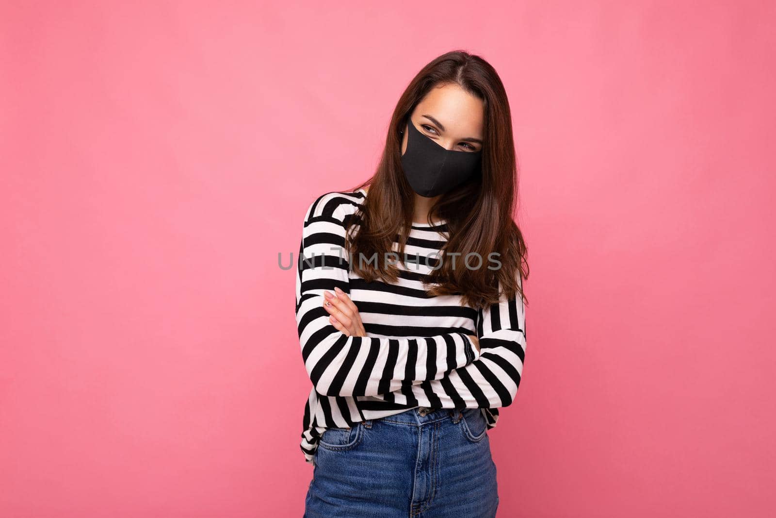 Young woman wearing an anti virus protection mask to prevent others from corona COVID-19 and SARS cov 2 infection isolated over pink background.