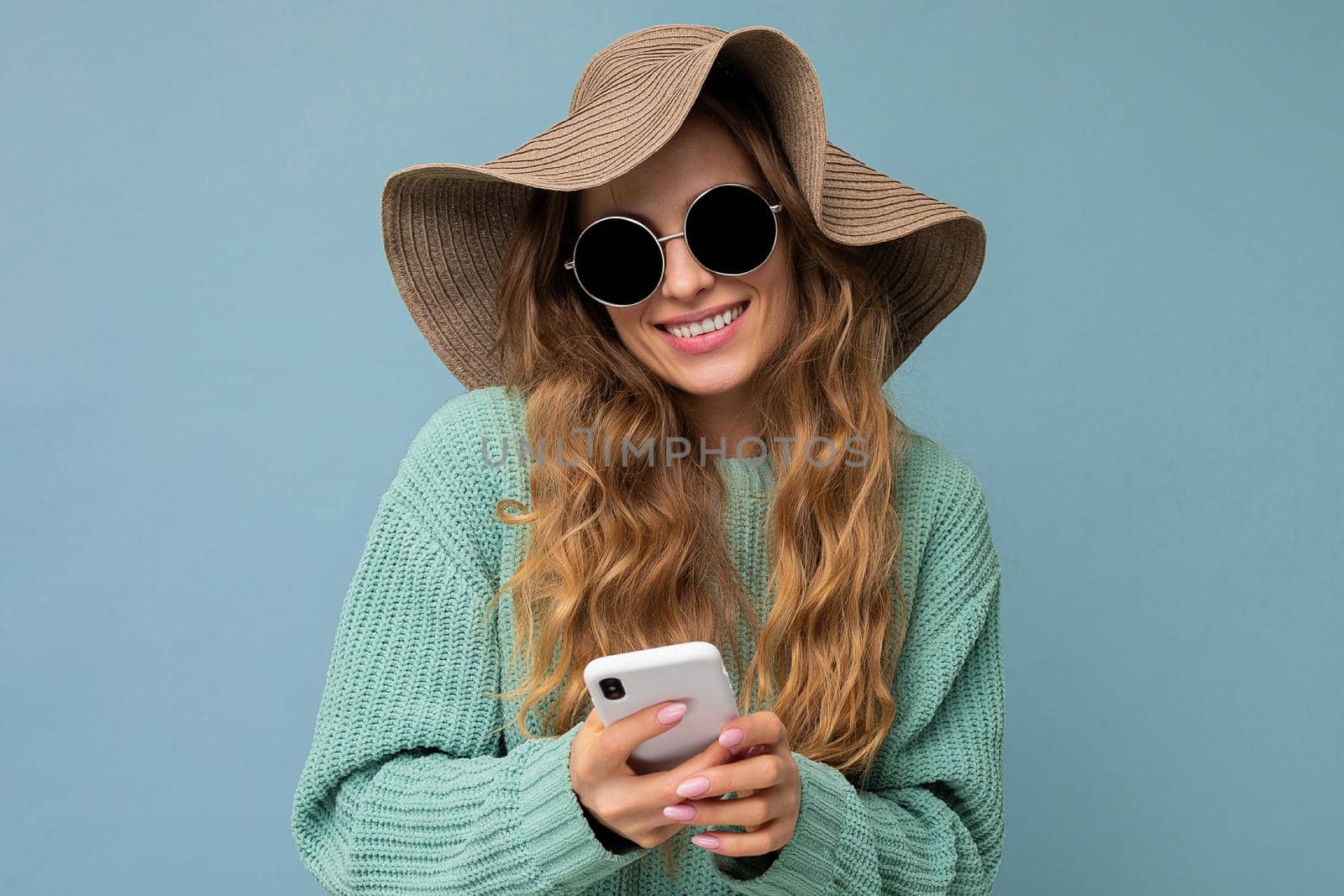 Beautiful young woman wearing casual clothes standing isolated over background surfing on the internet via phone looking at mobile screen.