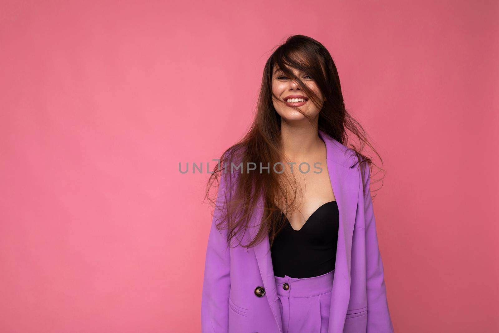 Portrait of positive delightful beautiful fashionable brunette woman in casual trendy violet jacket isolated on pink background with free space.