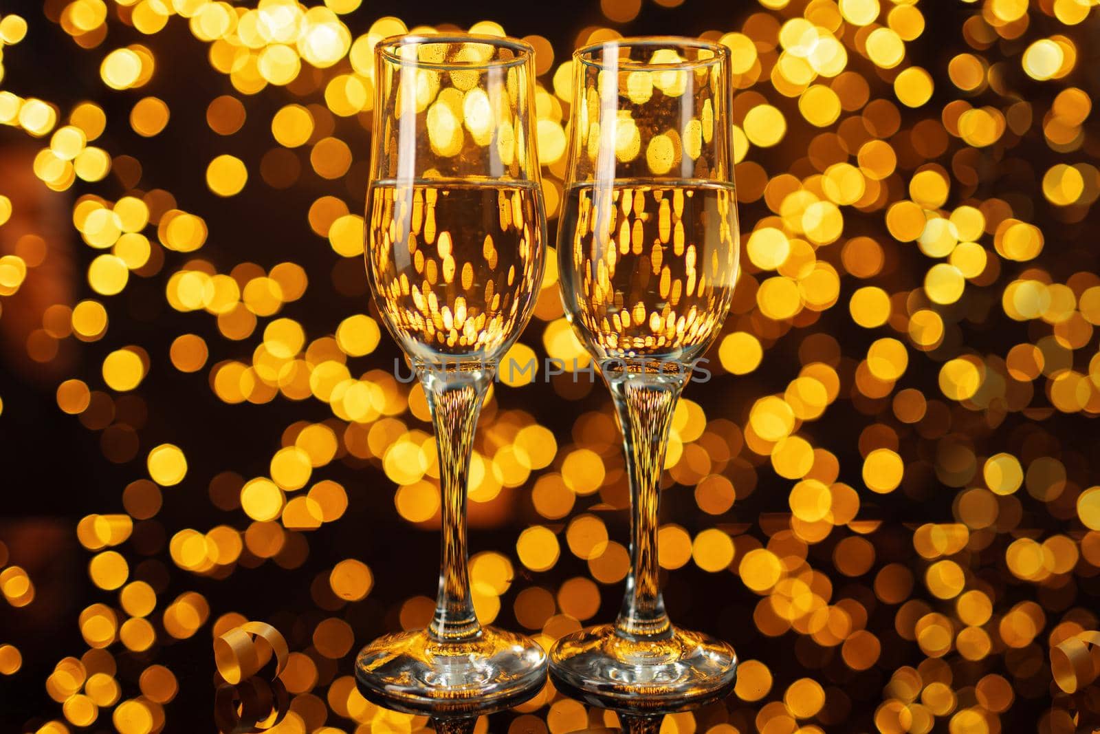 Two glasses of Champagne against shiny bokeh lights background