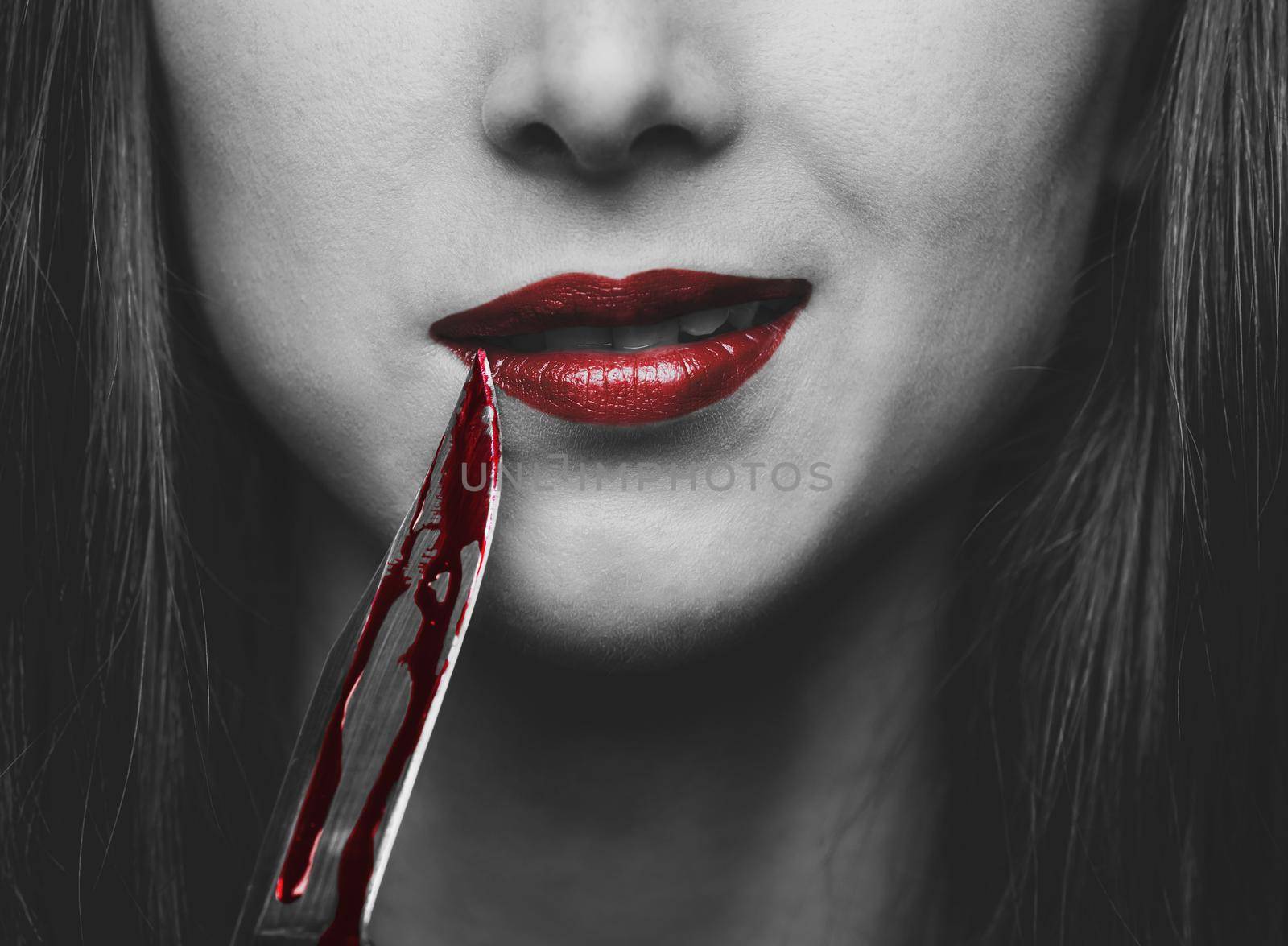 Smiling dangerous young woman with knife in blood. Halloween or horror theme. Black and white image with red elements