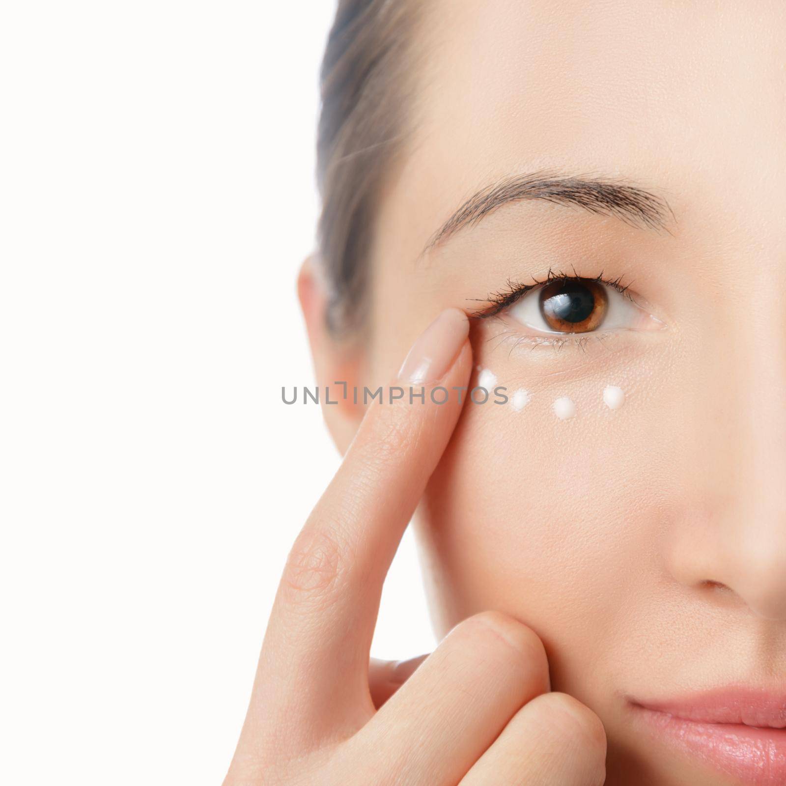 Portrait of beautiful woman, applying cream on her skin around eye