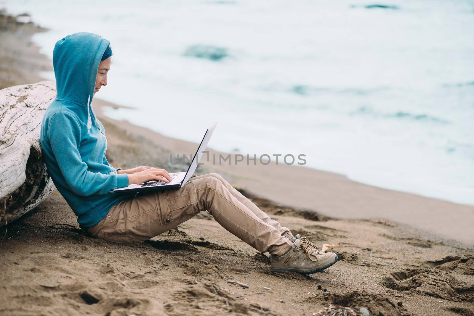 Freelancer young woman working on laptop on beach near the sea. Freelance concept