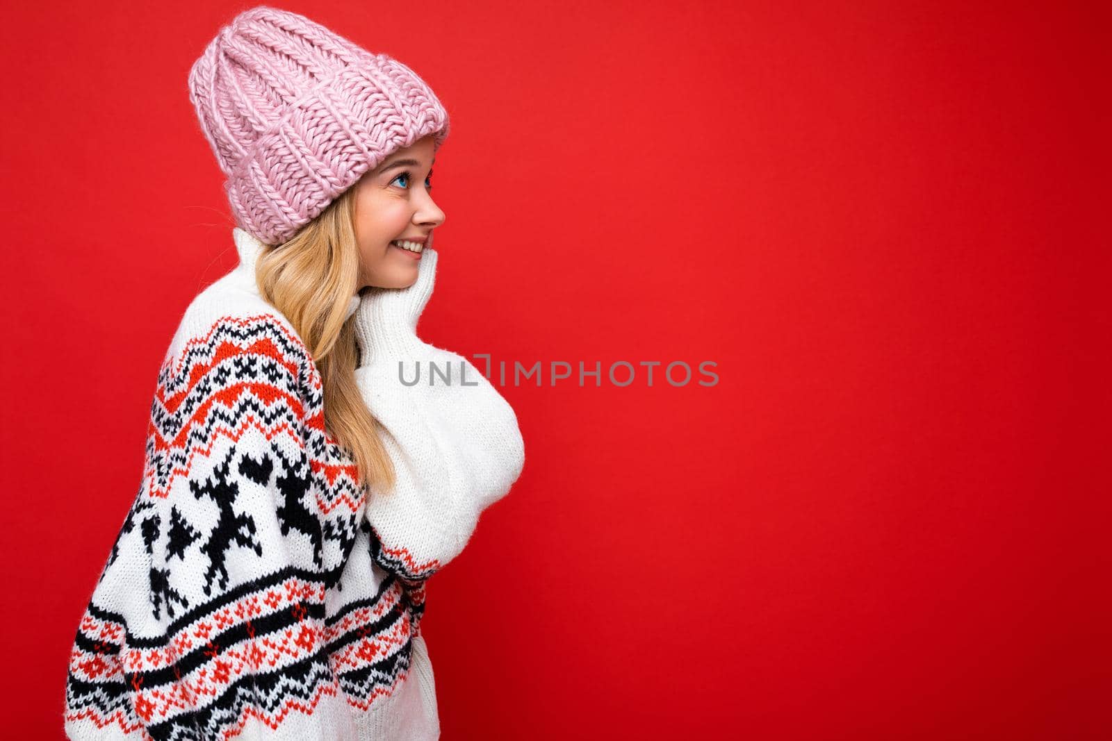 Side-profile photo of pretty smiling happy young blonde woman standing isolated over colourful background wall wearing everyday trendy clothes looking to the side. Empty space, copy space