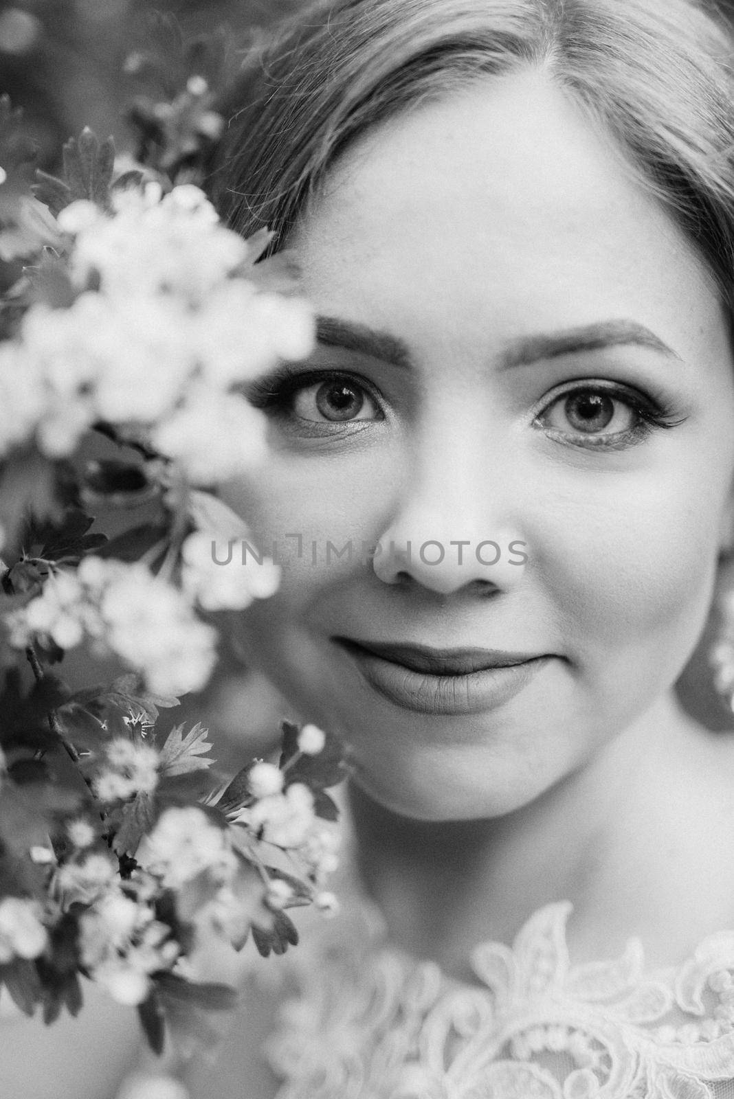 bride with a wedding bouquet in the forest near the bushes blooming with white flowers