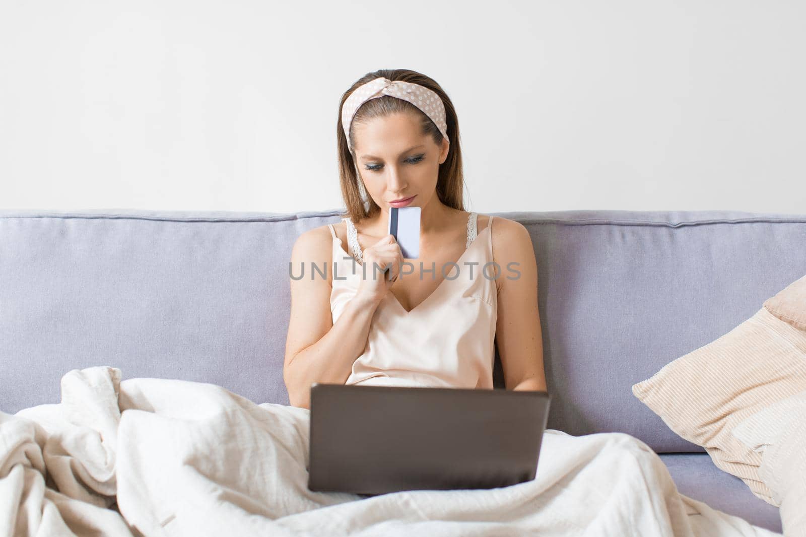 Woman dreams about purchasing through the internet. Front view of a woman with laptop in home interior.