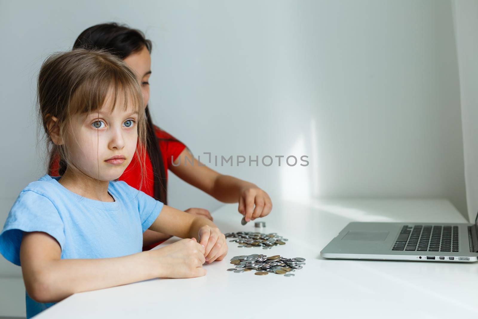 portrait of little girls sitting at table and calculating money
