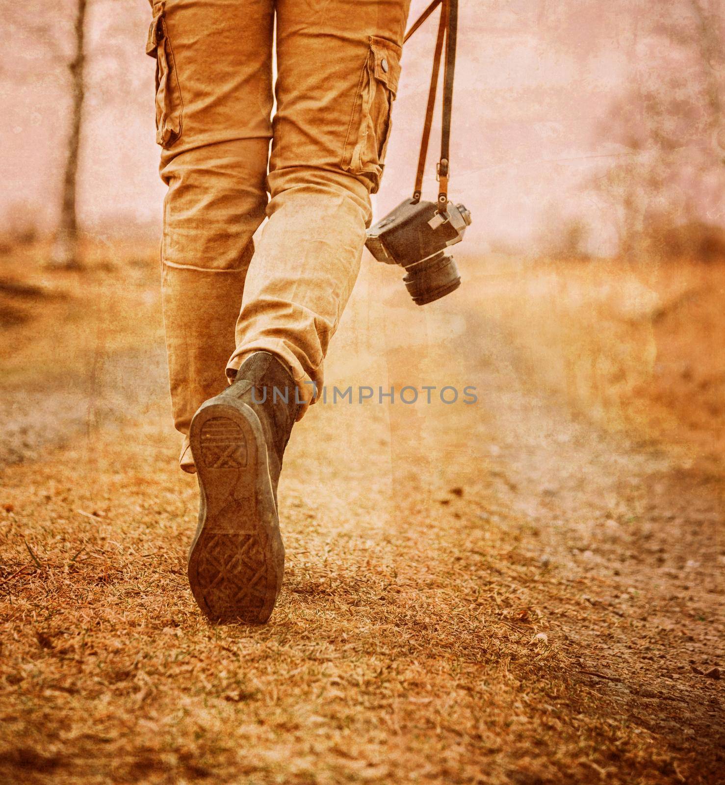 Traveler woman with old photo camera walks on a road, face is not visible