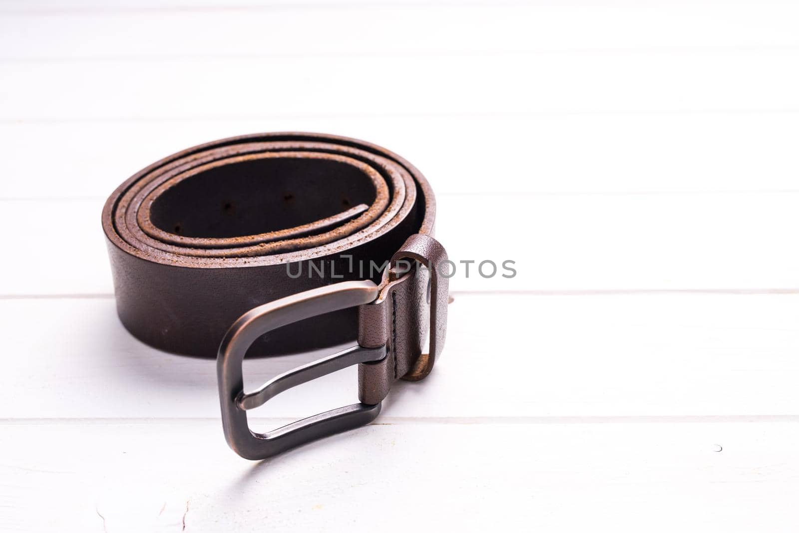 twisted brown leather belt on wooden background by GekaSkr