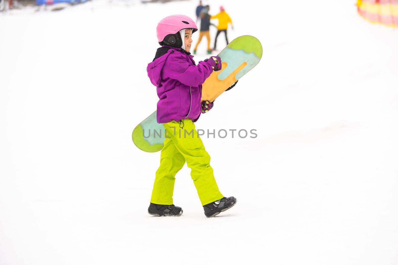 Snowboard Winter Sport. little girl learning to snowboard, wearing warm winter clothes. Winter background.