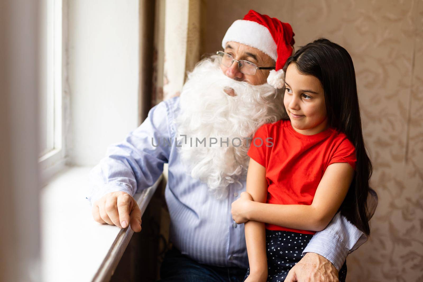Picture of an elderly man wearing a Santa hat while playing with his grandchildren