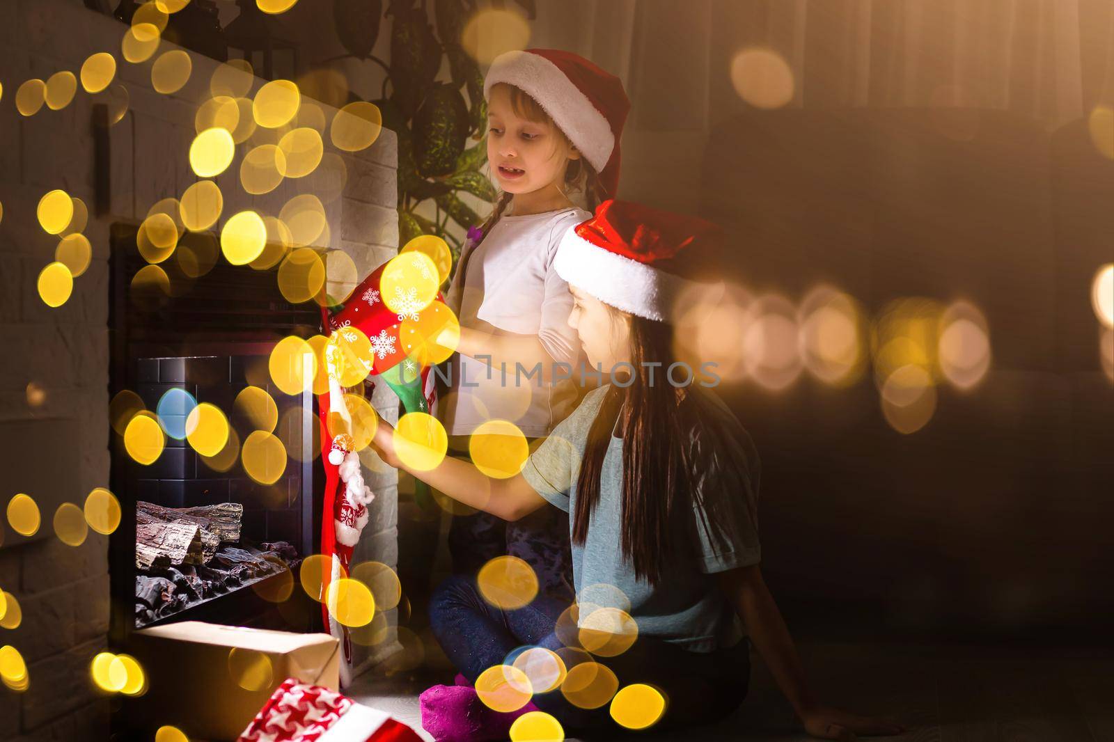 Little kids opening presents next to the fireplace in a cozy home celebrating Christmas