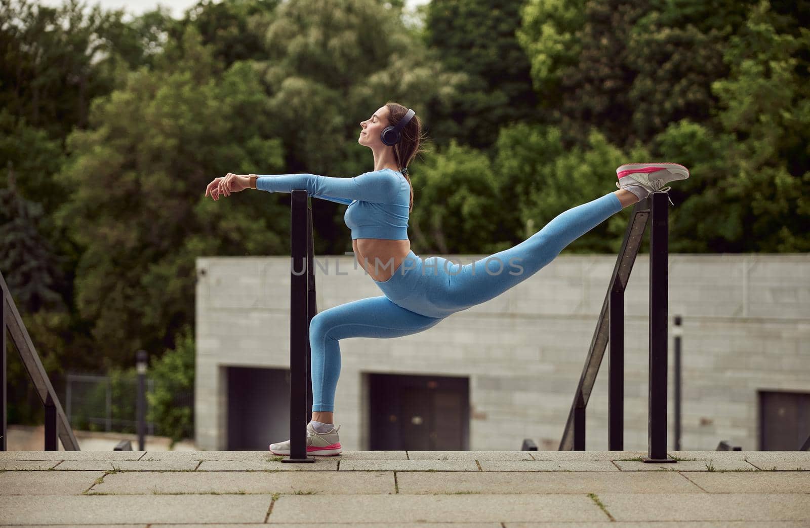 Beautiful fit caucasian woman is doing exercises outdoors at the city by Yaroslav_astakhov