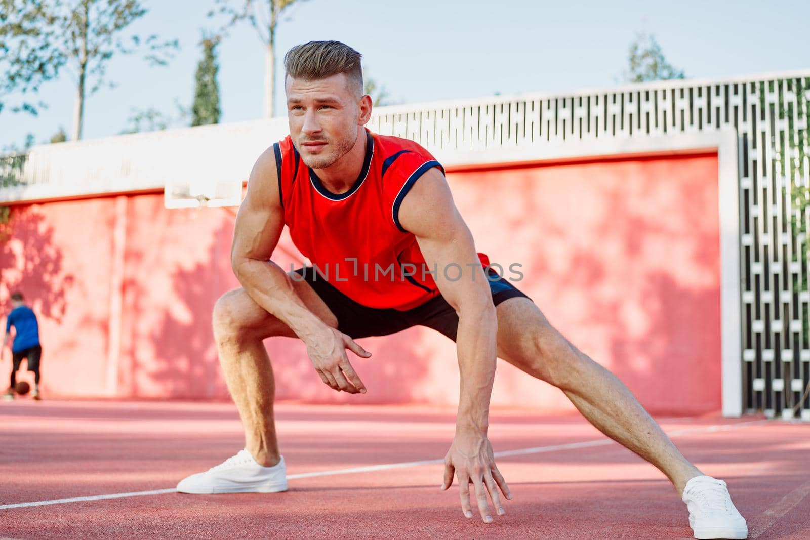 sports man in a red t-shirt on the sports ground doing exercises by Vichizh